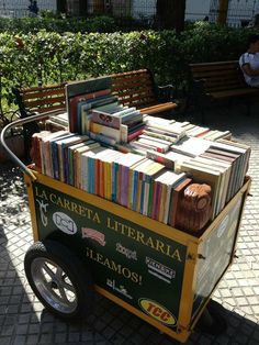 a cart filled with books sitting on top of a sidewalk