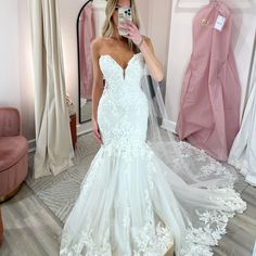 a woman is taking a selfie in her wedding dress while standing in the living room