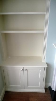 an empty white bookcase in the corner of a room