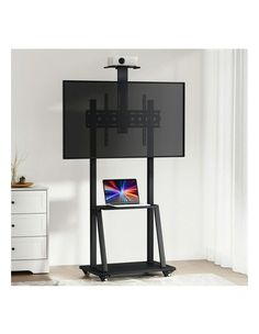 a tv stand with a laptop on top of it and a flat screen television mounted to the wall