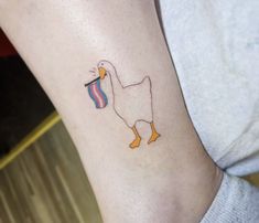 a duck with a piece of cake in it's beak tattoo on the leg