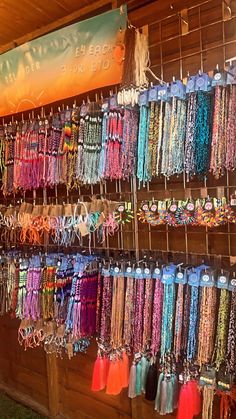 many different colored necklaces are hanging on the wall in front of a store window