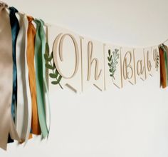 a banner with ribbons hanging from it's sides and the word oh, baby spelled in cursive letters