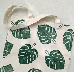 This organic cotton tote bag was printed by hand from hand-carved blocks.  Totes make great gifts! Hot tip: Use this monstera tote bag as an earth-friendly and practical gift gift bag, and fill it with other small goodies for your favorite plant-loving friend. CARE INSTRUCTIONS: Machine Wash in Cold Water Tumble Dry on Low Heat Iron on Reverse Green Eco-friendly Canvas Tote Bag, Green Eco-friendly Tote Canvas Bag, Green Canvas Bag With Eco-friendly Ink As Gift, Eco-friendly Hand Printed Canvas Bag For Everyday Use, Green Handmade Cotton Canvas Bag, Handmade Green Cotton Canvas Bag, Eco-friendly Hand Printed Canvas Bag For Daily Use, Eco-friendly Hand Printed Rectangular Canvas Bag, Eco-friendly Hand Printed White Canvas Bag