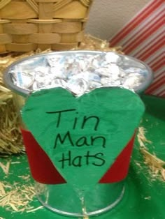 a tin man hat with candy in it on a green table next to straw bales