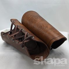 pair of brown leather boots with laces on the inside and outside, sitting on a white surface