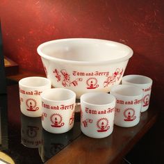 seven red and white glass cups sitting on top of a wooden table next to each other