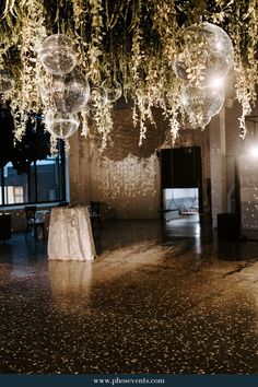 the ceiling is decorated with hanging glass balls and greenery for an elegant wedding reception