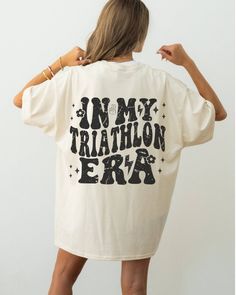 a woman wearing a white shirt that says, i'm my triathlon era