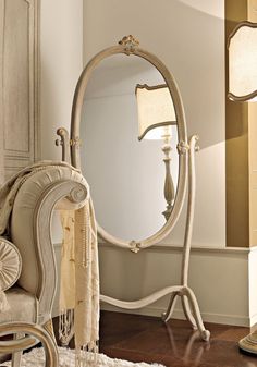 a white chair sitting next to a large mirror on top of a wooden floor in a room