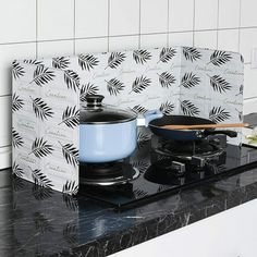 a stove top with a pot and pan on it next to a tile backsplash