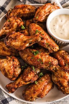 chicken wings on a plate with ranch dressing in the bowl and garnished with parsley