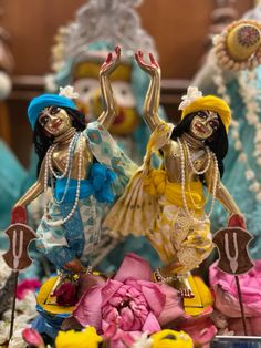 two figurines that are standing next to each other in front of some flowers