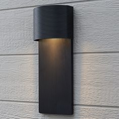 an outdoor wall light on the side of a house with white siding and wood paneling