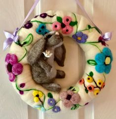 a stuffed animal sitting on top of a white wreath hanging from the side of a door