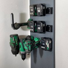 two green and black power tools are hanging on the wall