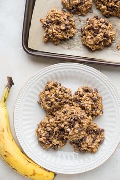 oatmeal cookies on a plate next to a banana and cookie sheet with chocolate chips