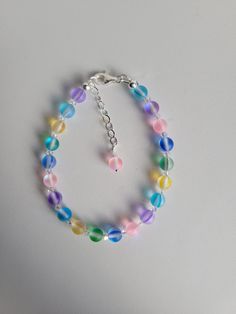 "The bracelet is made of 6 different colored Mystic Aura Quartz gemstone beads. This Quartz gemstone is translucent and has a glowing \"flash\" that becomes visible as the beads and moved. They are also known as Mermaid beads. Each bead is surrounded by 3mm Czech Clear AB crystal bicone beads. The bracelet is 7\" long with a 1\" beaded extension. Custom Orders are always welcome! Ask about free sizing." Hypoallergenic Rainbow Bracelets With Round Beads, Hypoallergenic Rainbow Beaded Bracelets, Iridescent Beaded Bracelets With Colorful Beads, Rainbow Crystal Bracelet With Round Beads, Adjustable Iridescent Crystal Bracelet, Handmade Iridescent Bracelets With Round Beads, Iridescent Adjustable Crystal Bracelet With 8mm Beads, Iridescent Adjustable Bracelets With 8mm Beads, Adjustable Iridescent Crystal Bracelet With 8mm Beads