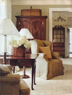 a living room filled with furniture and a basket on top of a table next to a lamp