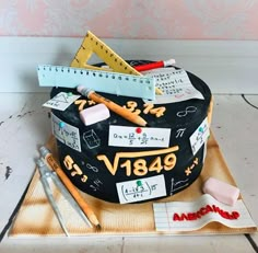 a cake that is on a tray with some writing and pencils in the middle