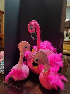 a pink flamingo sitting on top of a wooden floor next to a black wall