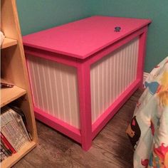 a pink toy chest sitting next to a book shelf