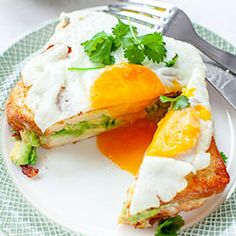 a white plate topped with an egg sandwich and orange wedges next to a fork