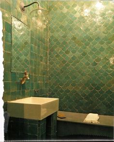 a green tiled bathroom with a sink and bathtub