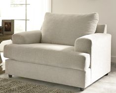 a living room with a white chair and a rug on the floor in front of a window