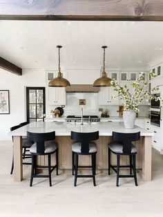 a large kitchen island with four stools and a vase filled with flowers on it