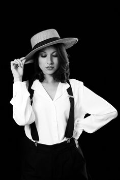 a woman wearing a hat and suspenders is posing for a black and white photo