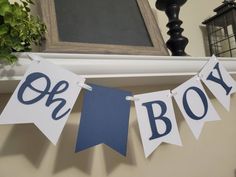 a blue and white banner with the word oh boy hanging on a mantle next to a potted plant