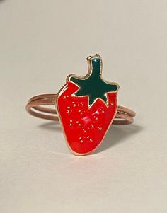 a red strawberry shaped ring sitting on top of a table