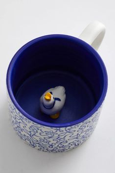 a blue and white cup with a yellow rubber ducky in the middle, on a white surface