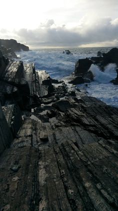 an ocean view with waves crashing on the rocks