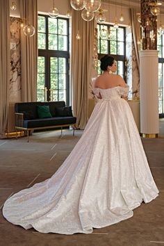 a woman in a white wedding dress looking at herself in a large room with chandeliers