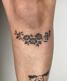 a tattoo on the leg of a man with flowers and a dog's head