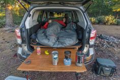 a man sitting in the back of a van with an open trunk and sleeping bag