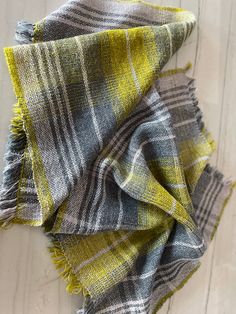 a yellow and grey plaid scarf laying on top of a wooden floor