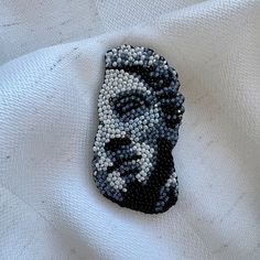 a beaded brooch depicting a man's face on a white t - shirt