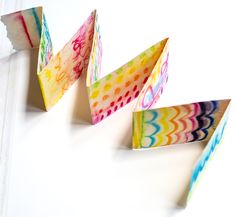 three colorful paper boats sitting on top of a white table next to each other,