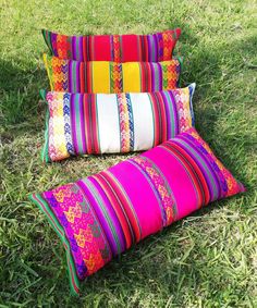 three colorful pillows laying on the grass