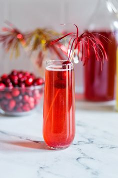 a glass filled with liquid sitting on top of a table next to some cranberries