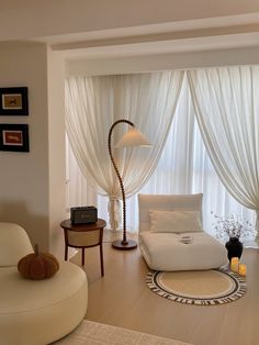 a living room with white furniture and drapes on the window sill, along with a round rug