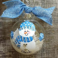 a glass ornament with a snowman on it's side and a blue bow