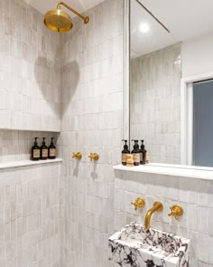 a bathroom with marble counter tops and gold faucets on the shower wall, along with two soap dispensers