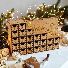 a wooden calendar sitting on top of a table next to christmas ornaments and lights in the background