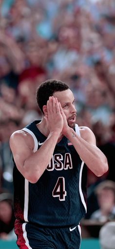 a basketball player holding his hands to his face while standing in front of an audience