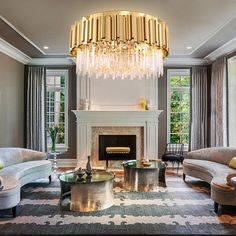 a living room filled with furniture and a chandelier hanging from the ceiling over a fire place