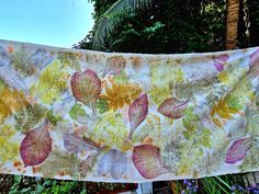 a cloth hanging from a clothes line in front of trees and bushes with leaves on it